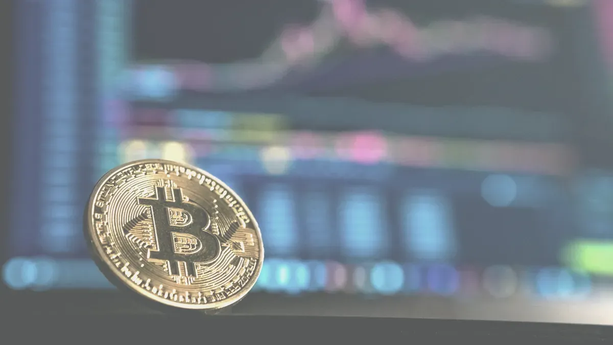 Ett bitcoinmynt framför en skärm med kursdiagram
